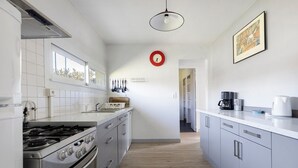 Una cocina con estufa, horno y armarios, una ventana y un reloj en la pared.