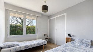Un dormitorio con cama, un banco, una silla, un escritorio y un armario.