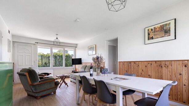 Un comedor moderno con una mesa blanca, sillas negras y un sillón antiguo.