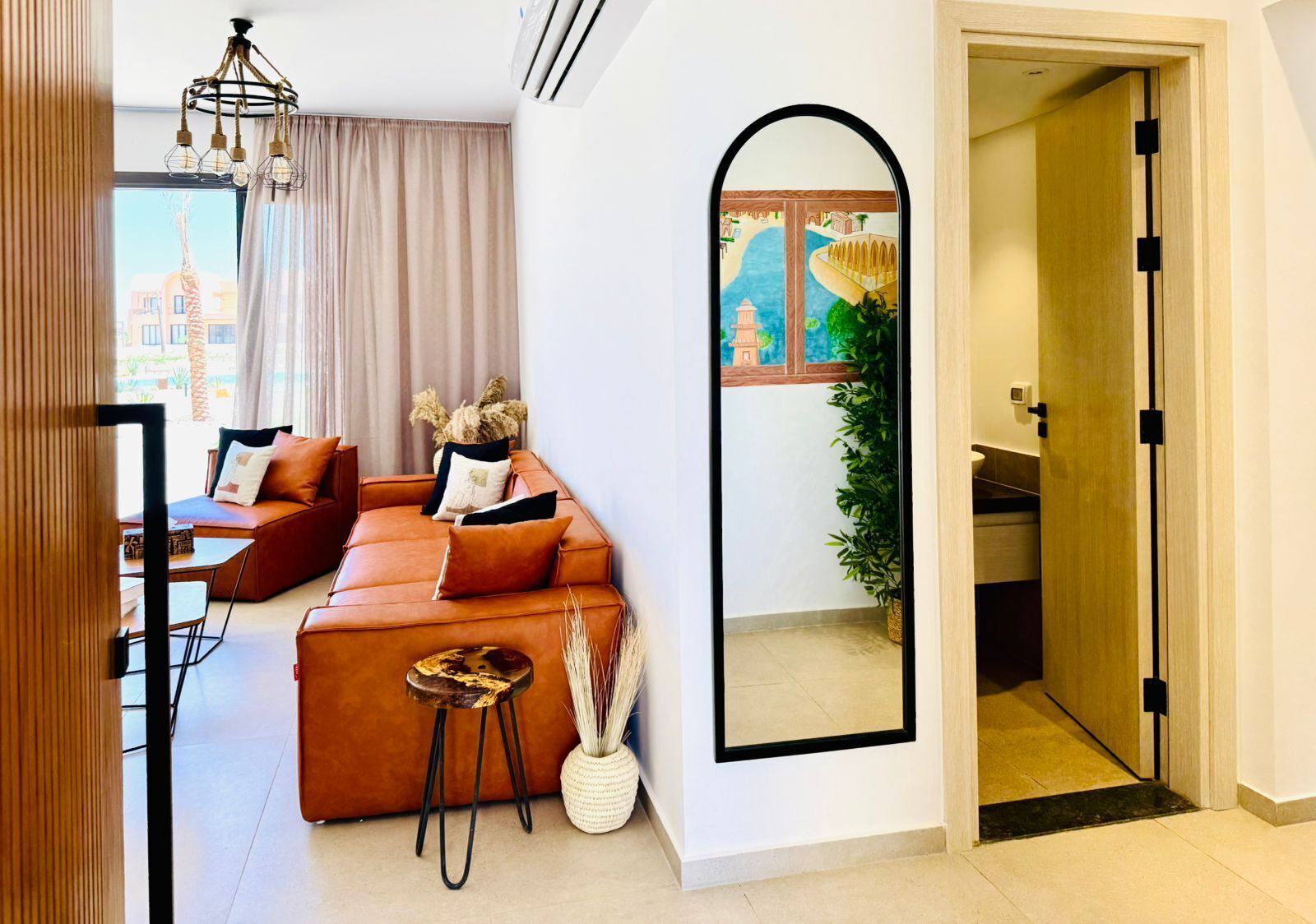A modern living room with a brown sofa, a small side table, and a mirror on the wall.