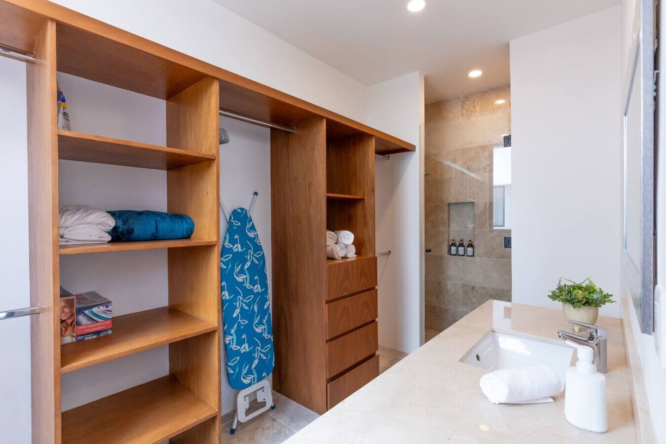 Une salle de bain moderne avec un grand miroir, un lavabo et un espace douche.