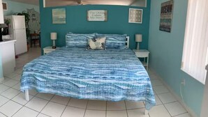 Une chambre à coucher avec un lit, deux tables de chevet, une horloge murale et une affiche.