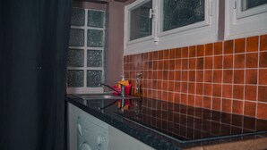 Una cocina con lavadora, lavaplatos y ventana con vidrio esmerilado.