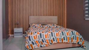 Un dormitorio con cama, mesita de noche y pared de listones de madera con luces LED.