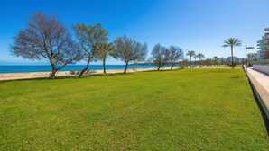 Un parque con césped, árboles y vista al mar.
