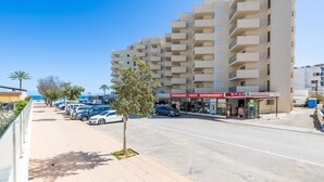 A multi-story building with balconies, a supermarket, and a parking area. - Incredible Sea Views – 50 m from Cala Millor Beach (Cala Millor)