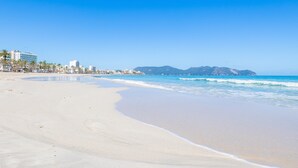 Una spiaggia con cielo sereno, una riva sabbiosa e edifici sullo sfondo.