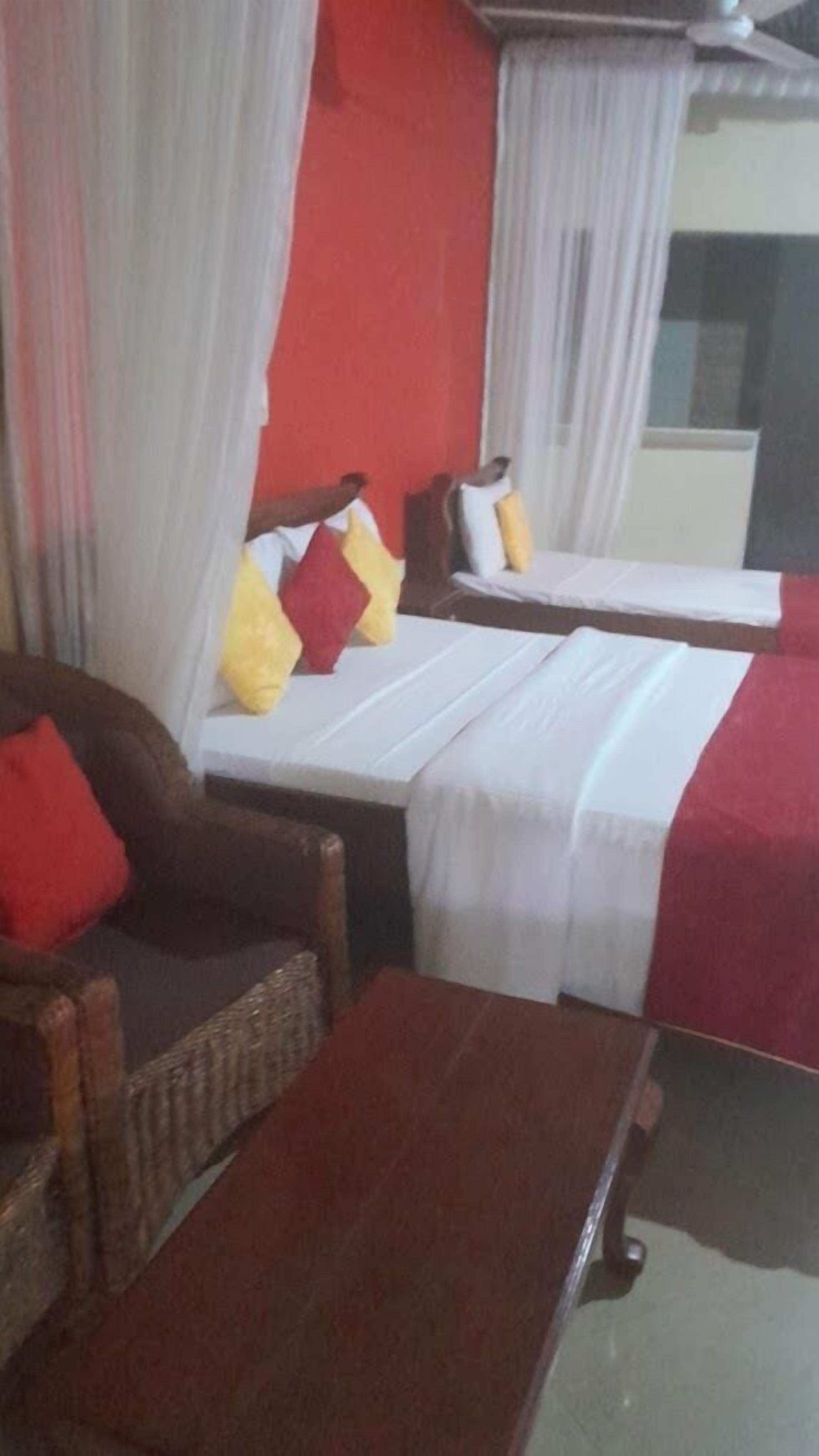 A hotel room with two single beds, a sofa, and a wooden table.
