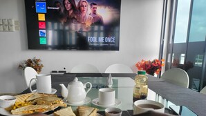 A dining table with sandwiches, a teapot, cups, and a bottle of juice. - Vievely Suites and Apartments (Lagos)