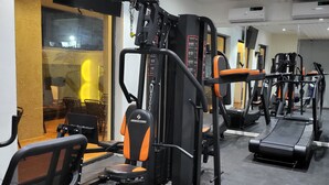 A gym with various exercise machines, a treadmill, and a seating area with chairs. - Vievely Suites and Apartments (Lagos)