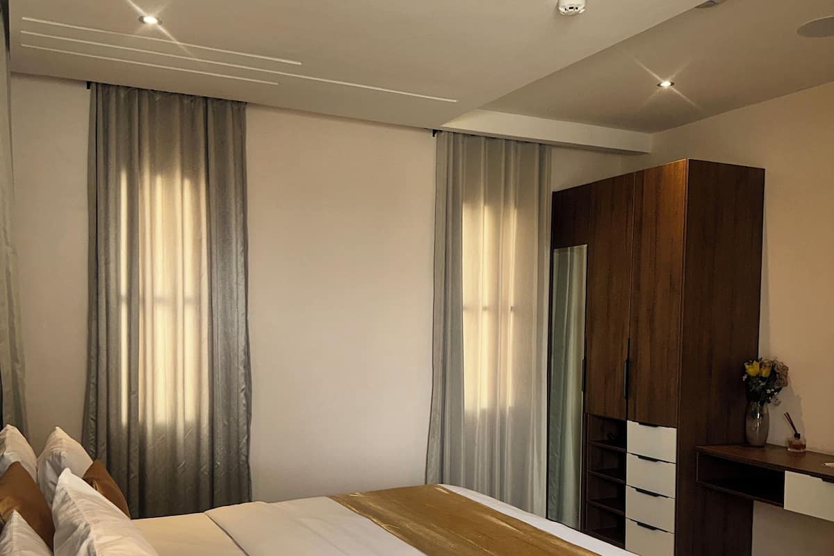 Una habitación de hotel con una cama grande, un armario de madera y un escritorio con un jarrón de flores.