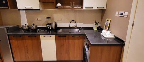 A compact kitchen with wooden cabinets, a built-in dishwasher, a sink, and a stove.