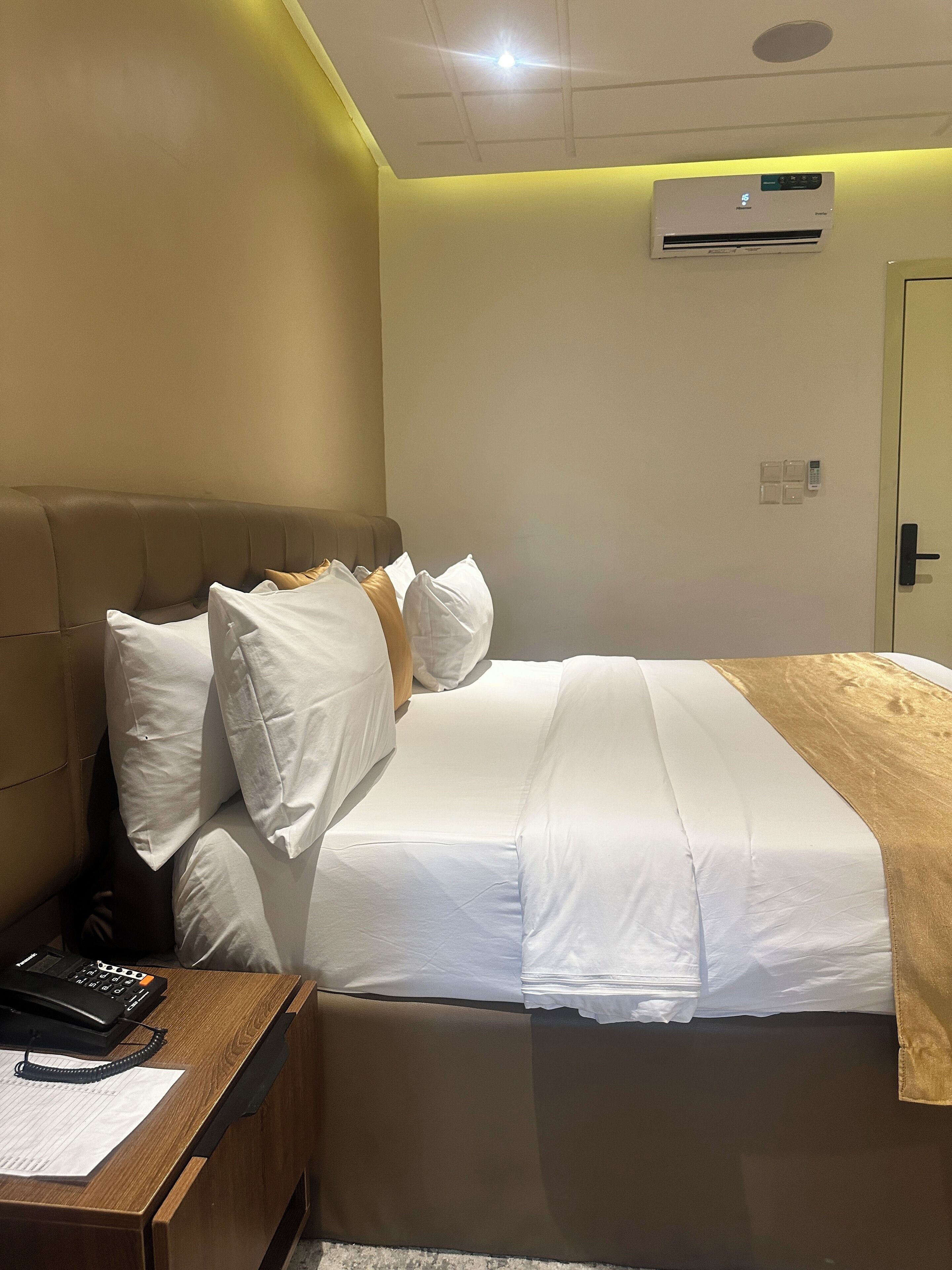 Une chambre d’hôtel équipée d’un lit, d’une table de chevet et d’un appareil de climatisation.