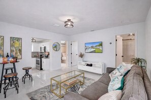 A modern living room with a sofa, coffee table, and kitchen area visible in the background. - 2-bedroom apartment in fantastic Miami with cool AC and comfort (Miami)