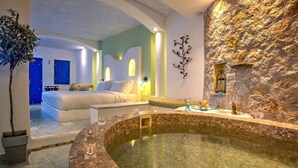 A spa area with a hot tub, a bed, and a stone wall. - Althene Suite, Divine Sea and Caldera Views,Furnished Balcony, Indoor Jacuzzi (Santorini)