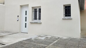 A building with a white facade, a red roof, a door, and two windows with metal bars. - Maisonnette Grande Hauteur Near Paris & Stade De France (Drancy)