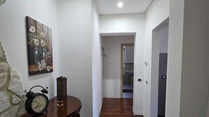 A hallway with wooden flooring, a painting on the wall, and a table with a clock. - How to Grandparents' House Narni (Umbria)