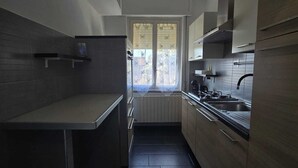 A modern kitchen with dark tiles, a built-in stove, and a window with a view. - How to Grandparents' House Narni (Umbria)