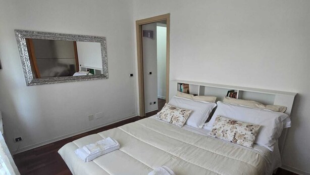 A bedroom with a large bed, a mirror, and a door leading to another room. - How to Grandparents' House Narni (Umbria)