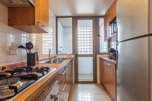 Una cocina moderna con electrodomésticos de acero inoxidable, armarios de madera y vistas a través de un ventanal.