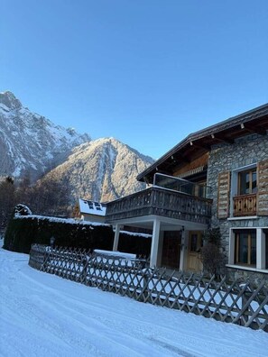 Un bâtiment en pierre doté d’un balcon, avec une chaîne de montagnes en arrière-plan.