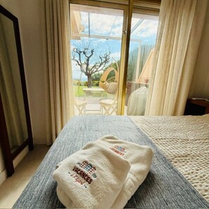 A hotel room with a bed, a window with curtains, a view of the outdoors, and a towel with text on it. - 45.50 S'Agaró Montecarlo with private garden (Sant Feliu de Guixols)
