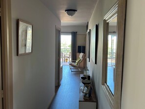 A hallway with a wooden floor, framed artwork on the walls, and a seating area with chairs and a table. - 26.00 Creu St Pol G5 Terrace and views next to the beach (S´agaro)