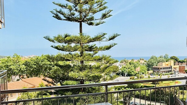 Ein Balkon mit Tisch und Stühlen, mit Blick auf einen Baum und die Stadt.