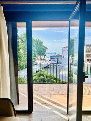 Ein Balkon mit Blick auf einen Strand, ein geparktes Auto und Gebäude im Hintergrund.
