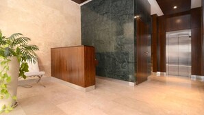 Een receptie met een balie, een marmeren muur en een moderne lift.