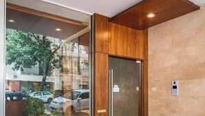 Een modern interieur met een houten paneelwand, een glazen deur en een weerspiegeling van het buitenlandschap.