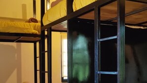 Une chambre avec un lit superposé, un sol carrelé et un plafond en bois.