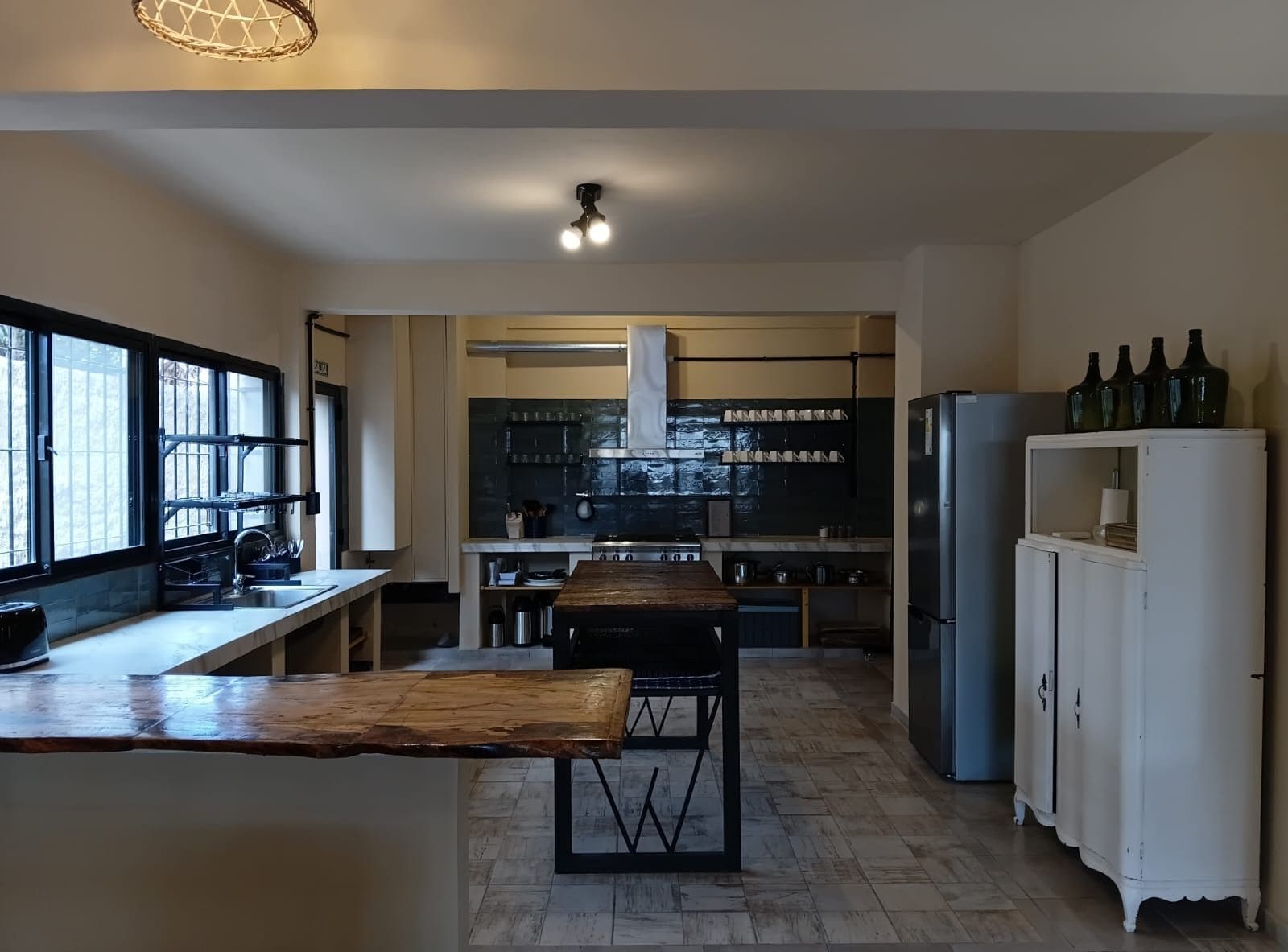 A kitchen with a wooden island, a built-in stove, and a white cabinet with bottles.