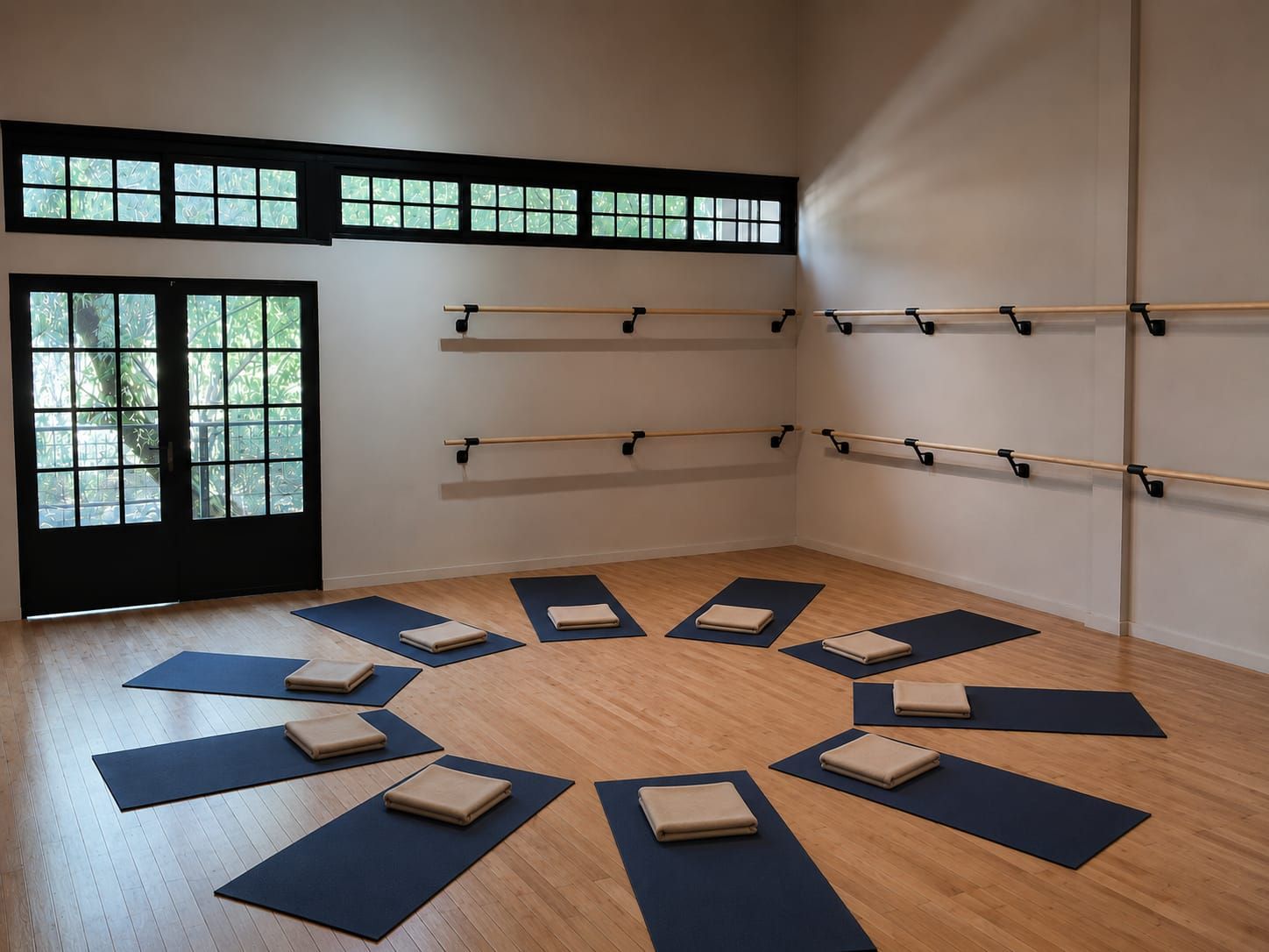 Una habitación con piso de madera, colchonetas de ejercicio dispuestas en círculo y barras de gimnasia fijadas a la pared.