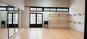 A spacious room with a wooden floor, large windows, and ballet barres on the wall. - Hostel Waysanu (Capilla del Monte)