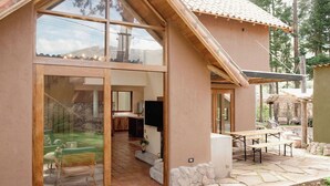 A modern house with a large glass door leading to a patio area with a stone floor and outdoor furniture.