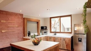 A kitchen with a wooden island, a refrigerator, and a window with a view of buildings.