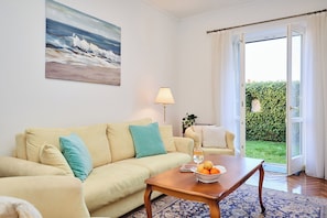 A living room with a sofa, a coffee table with fruit, a lamp, and a painting on the wall. - Green Horizon (Dubrovnik)