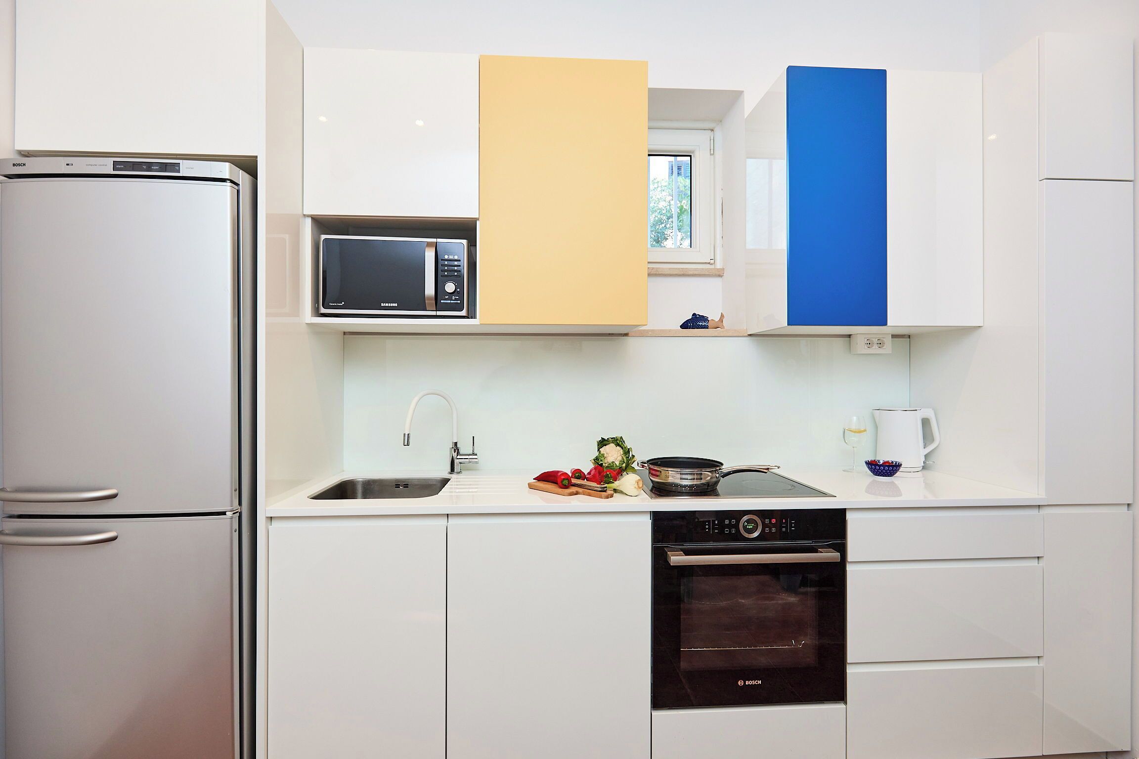 A kitchen with a refrigerator, microwave, oven, and sink.