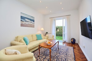 A living room with a sofa, a coffee table, a TV, and a view of the outdoors. - Green Horizon (Dubrovnik)