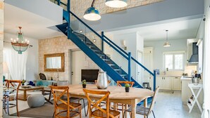 A spacious living area with a large wooden dining table, blue staircase, and a kitchen area. - Villa Melyssaia, Private Pool and Garden, Spacious Furnished Terrace, Zakynthos (Zakynthos)