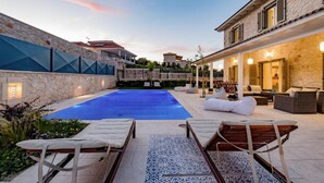 A poolside area with lounge chairs and a stone building with a balcony. - Villa Melyssaia, Private Pool and Garden, Spacious Furnished Terrace, Zakynthos (Zakynthos)