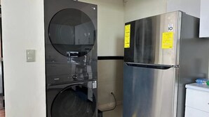 Una cocina compacta con refrigerador de acero inoxidable y lavadora y secadora integradas.