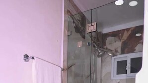 Een badkamer met een douche met glazen wand, een wit toilet en een wand betegeld met marmer.