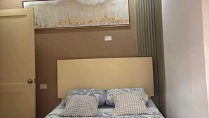 Een slaapkamer met een bed, een plafondventilator, een lamp, een kunstwerk aan de muur en een deur.