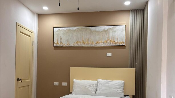 Een slaapkamer met een bed, een plafondventilator en een kunstwerk aan de muur.