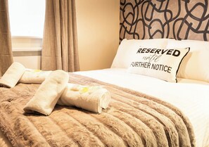 A hotel room with a bed, a pillow with "RESERVED until further notice" text, and rolled towels on the bed. - Warm & Welcoming Paisley Stay Near Transport Links - Pass the Keys (Paisley)
