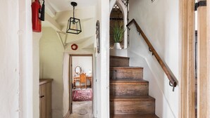 Un escalier en bois, doté d’une rampe et d’un extincteur rouge fixé au mur.