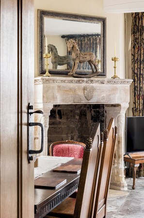 A room with a stone fireplace, a mirror with a horse sculpture, and a dining table with chairs. - Unique Castle Stay, The East Gate Tower, Warwick - Pass the Keys (Warwick)