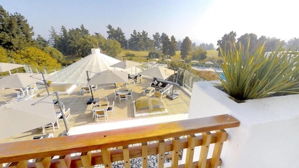 A rooftop terrace with sun loungers, umbrellas, and a large plant. - Hotel Marbella Resort (Puchuncavi)